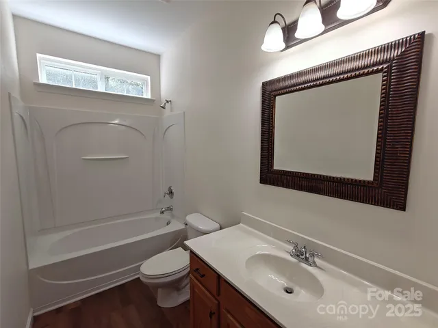 a bathroom with a toilet sink vanity tub and mirror