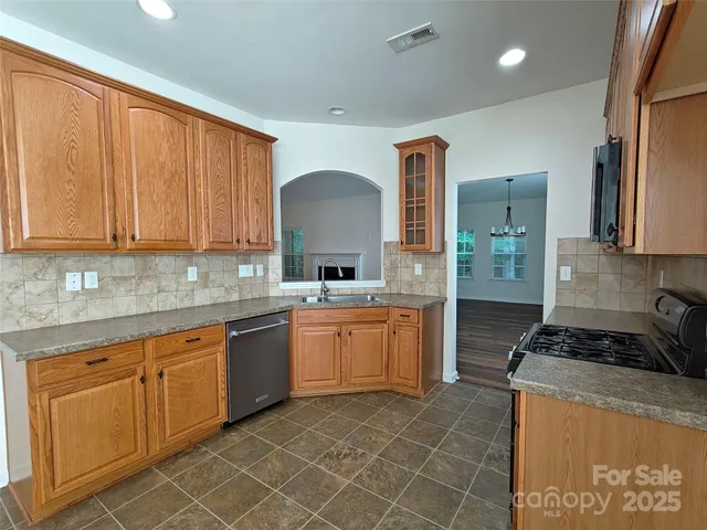 a kitchen with stainless steel appliances granite countertop a stove a sink and a refrigerator