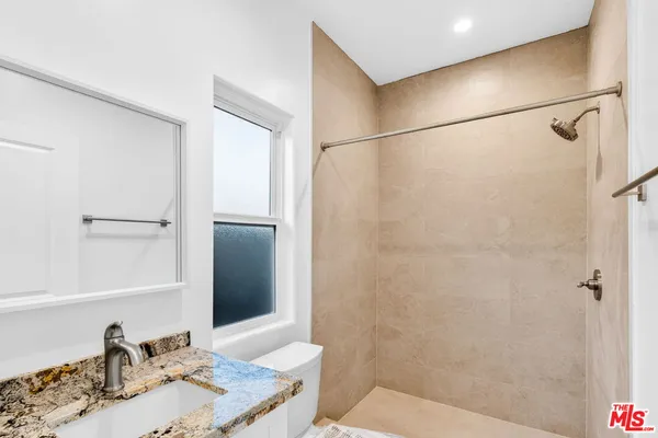 a bathroom with a granite countertop shower sink and a mirror