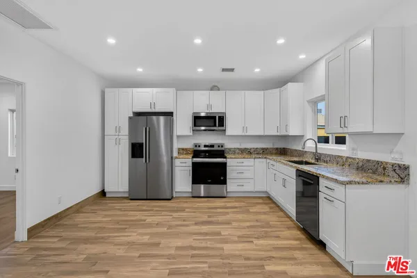 a kitchen with granite countertop white cabinets and stainless steel appliances