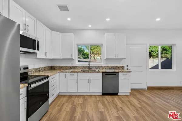 a kitchen with granite countertop white cabinets and appliances