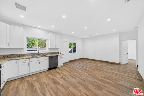 a kitchen with granite countertop a stove sink and cabinets