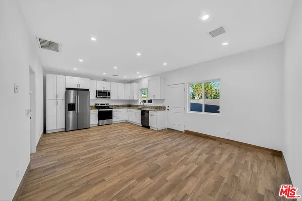 a view of kitchen with kitchen island granite countertop stainless steel appliances refrigerator oven stove top oven and cabinets