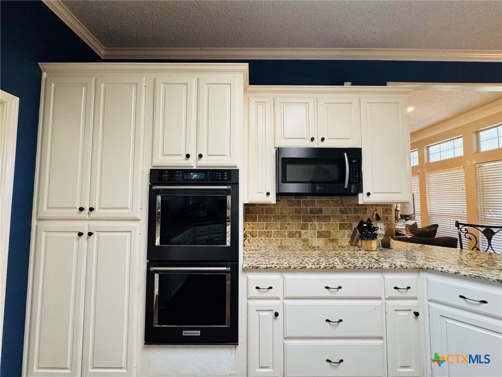 115 Oak Ridge Road Gatesville, TX 76528 - Photo 12 of 37 a kitchen with granite countertop white cabinets and stainless steel appliances