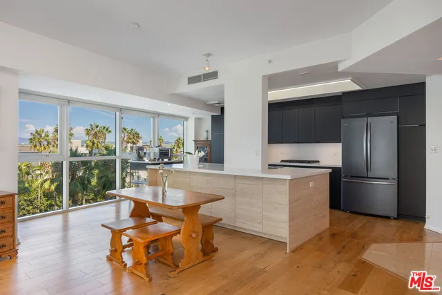 a living room with stainless steel appliances kitchen island granite countertop a table chairs and a refrigerator