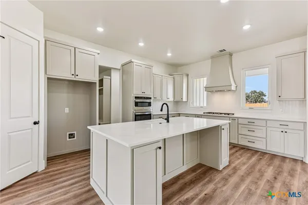 a kitchen with a sink a stove a refrigerator and white cabinets