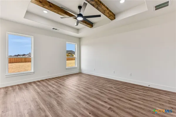 a view of an empty room with a window and wooden floor