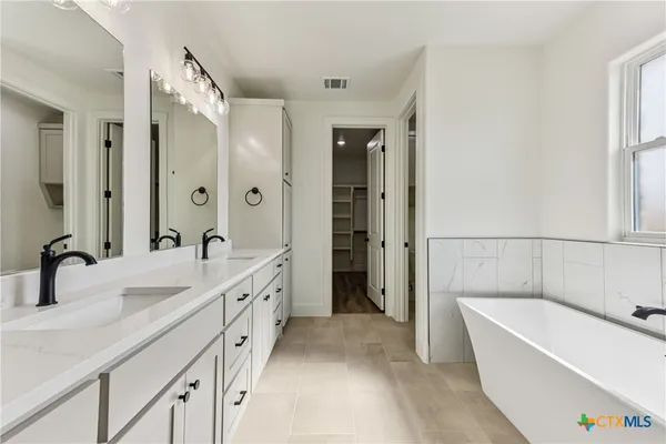a bathroom with a double vanity sink mirror double and bathtub