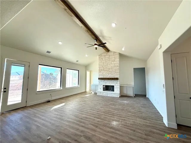 an empty room with wooden floor fireplace and windows