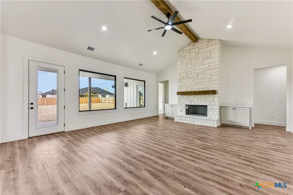 a view of an empty room with wooden floor fireplace and a window