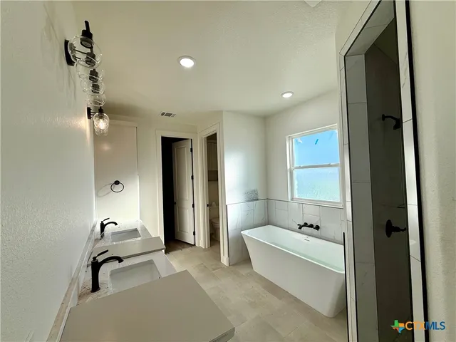 a bathroom with a tub shower and mirror
