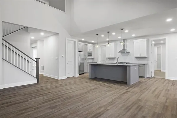 a large kitchen with stainless steel appliances granite countertop a large counter top and wooden floors
