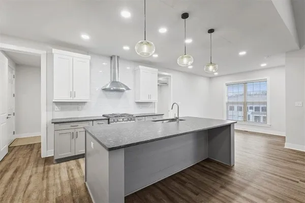 a kitchen with stainless steel appliances granite countertop a sink a stove and a wooden floors