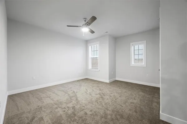 an empty room with chandelier fan and windows