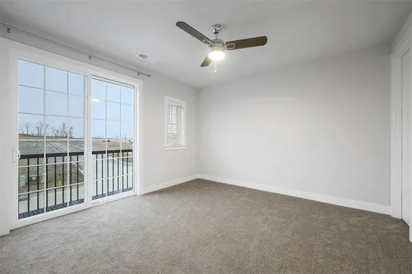 an empty room with a ceiling fan and carpet