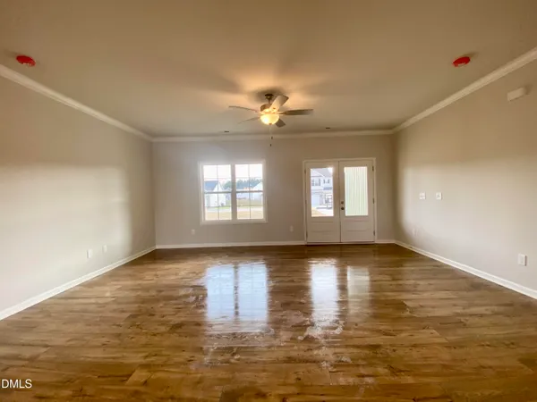 a view of an empty room with wooden floor and a window