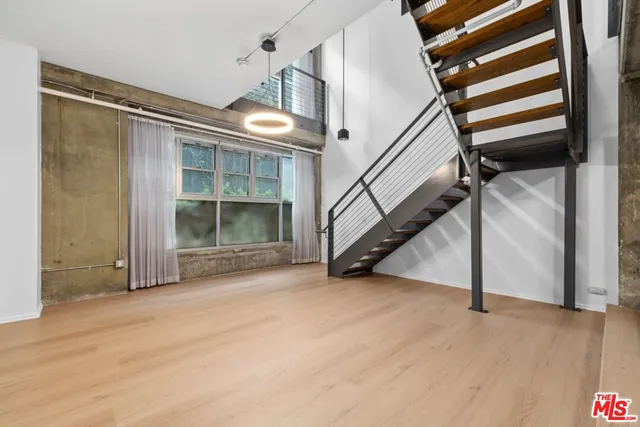 a view of an empty room with wooden floor and stairs