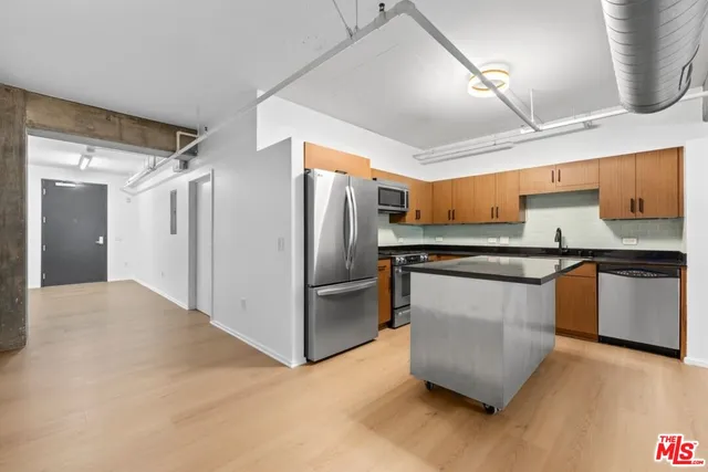 a kitchen with stainless steel appliances granite countertop a refrigerator a sink and a stove