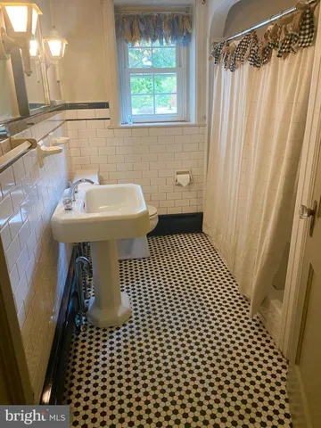 a bathroom with a sink a toilet a window and shower