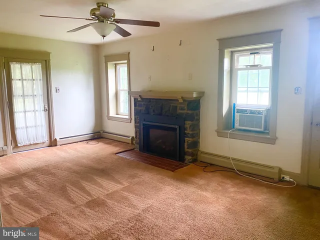 an empty room with windows fireplace and fan