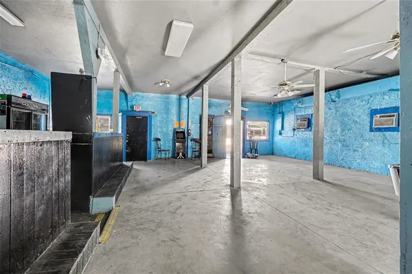 a view of a hallway with stainless steel appliances a refrigerator and a fireplace