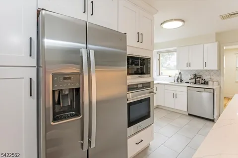 a large white kitchen with kitchen island a sink a counter top and stainless steel appliances