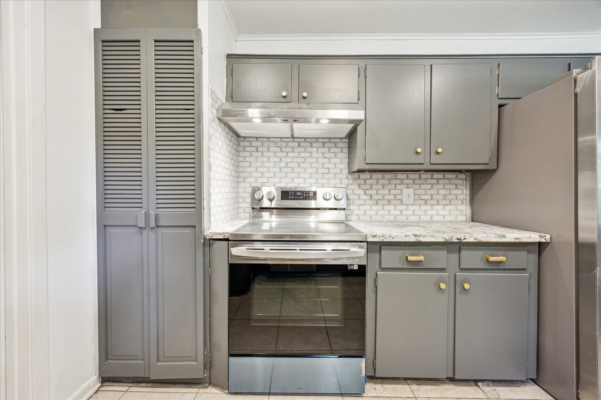 5419 Beechnut Street Houston, TX 77096 - Photo 12 of 28 Kitchen detail featuring stainless range with vent hood, beautiful tile backsplash, and great cabinet storage.