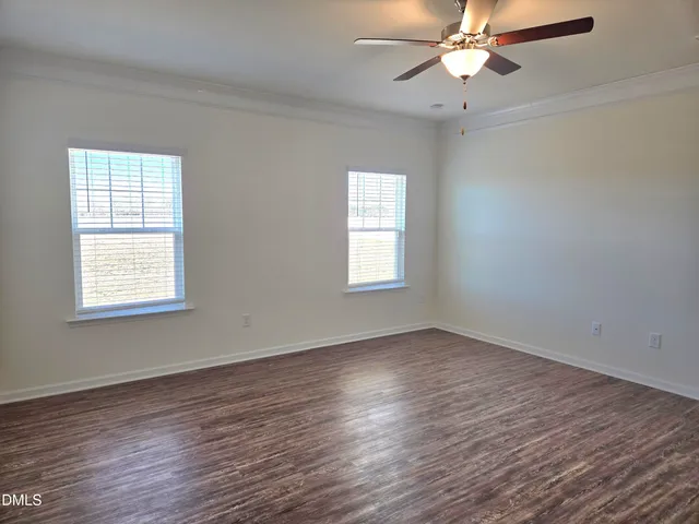 an empty room with wooden floor fan and windows
