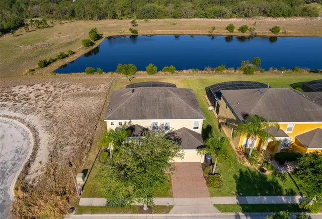 an aerial view of a house with a lake yard and outdoor seating