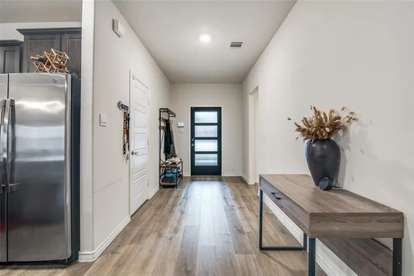 a living room with stainless steel appliances furniture a refrigerator and a wooden floor
