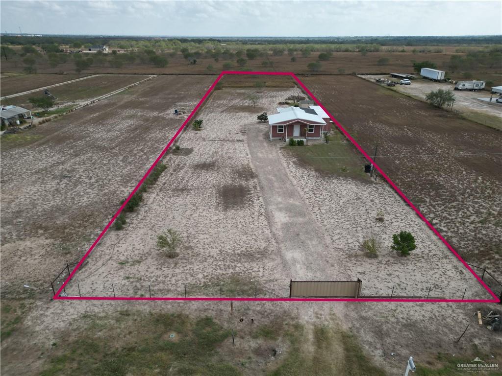 189 Midway Road Rio Grande City, TX 78582 - Photo 15 of 20 Expansive land parcel featuring a detached single-story residence with a red exterior and white trim, a metal roof, and a covered front porch
