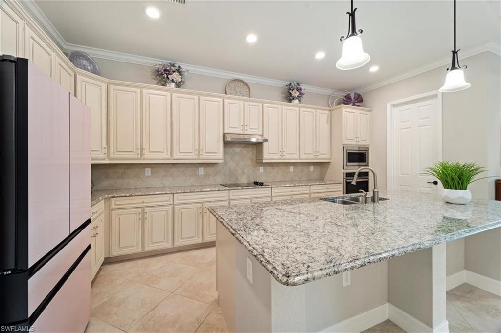 12840 Kinross Lane Naples, FL 34120 - Photo 10 of 44 a kitchen with kitchen island granite countertop a sink a counter space appliances and cabinets