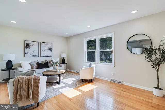 a living room with furniture large window and wooden floor