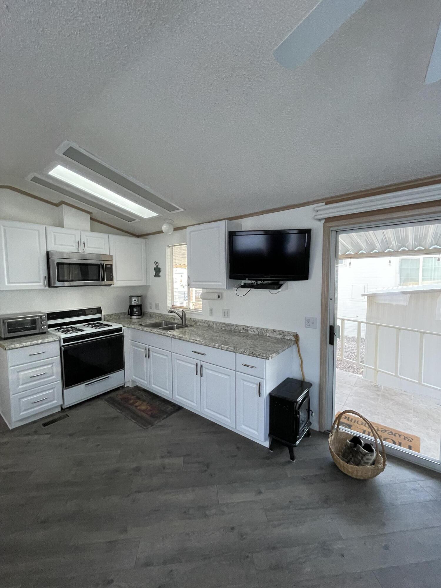 81620 Ave 49, Unit 27A Indio, CA 92201 - Photo 16 of 22 a kitchen with furniture a stove and a wooden floor