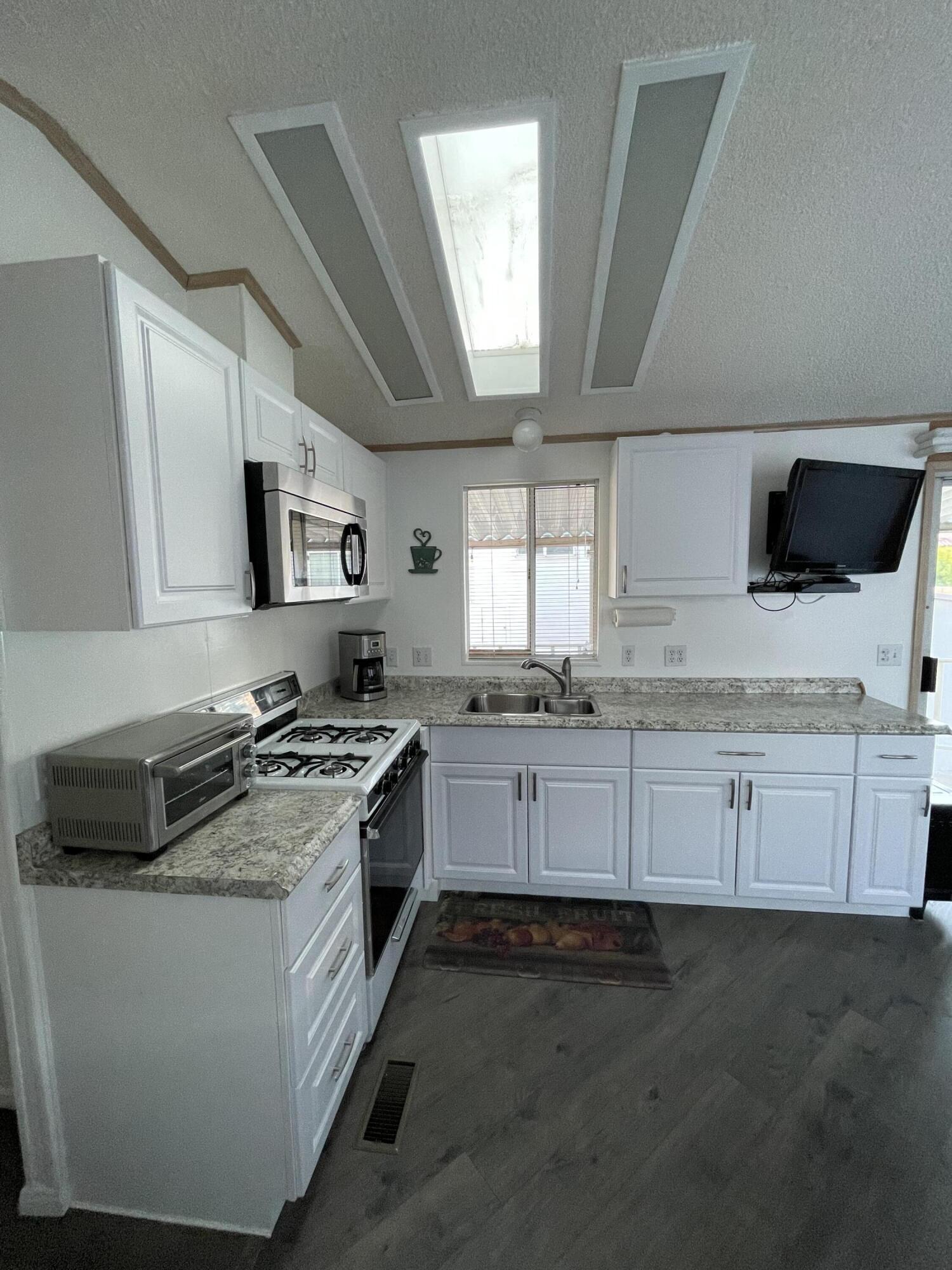 81620 Ave 49, Unit 27A Indio, CA 92201 - Photo 4 of 22 a kitchen with granite countertop white cabinets and white appliances
