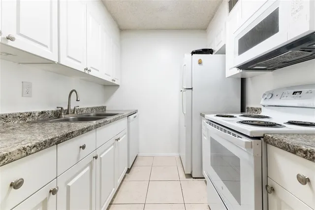 a kitchen with granite countertop a sink stove and cabinets