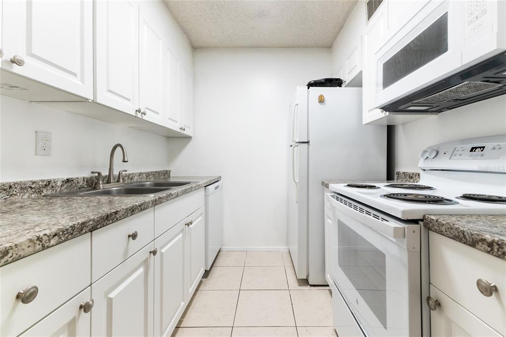 6519 West Newberry Road, Unit 805 Gainesville, FL 32605 - Photo 12 of 39 a kitchen with granite countertop a sink stove and cabinets