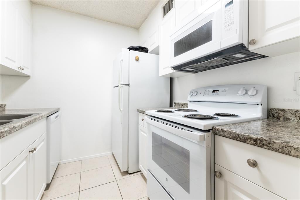 6519 West Newberry Road, Unit 805 Gainesville, FL 32605 - Photo 15 of 39 a kitchen with granite countertop cabinets a stove and a sink