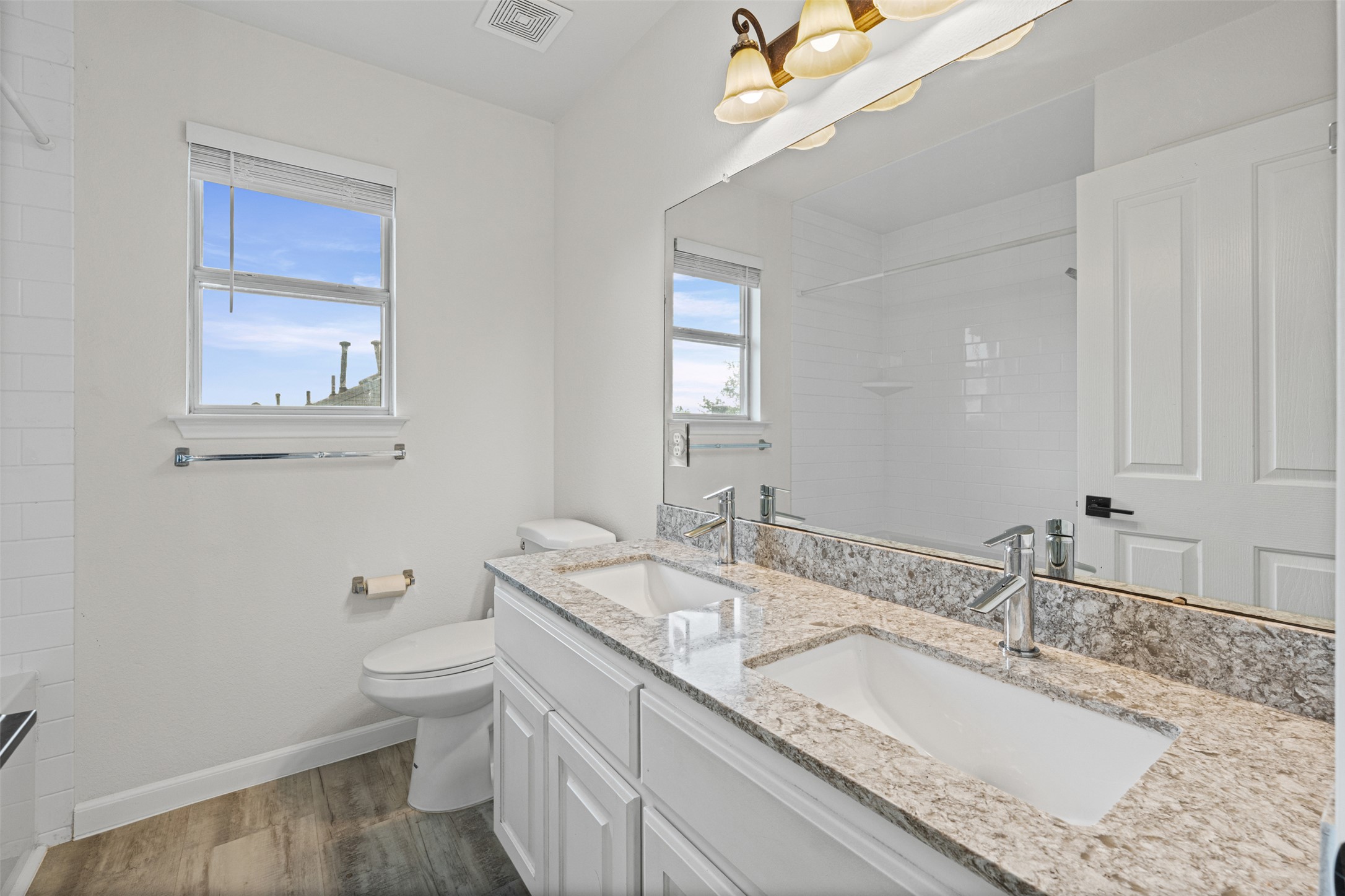 8820 Colberg Drive Austin, TX 78749 - Photo 25 of 35 Dual vanities with granite counters and rich wood-look flooring adorn this immaculate bathroom.
