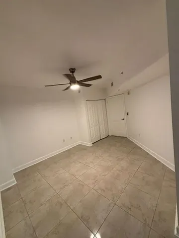 an empty room with a ceiling fan and window