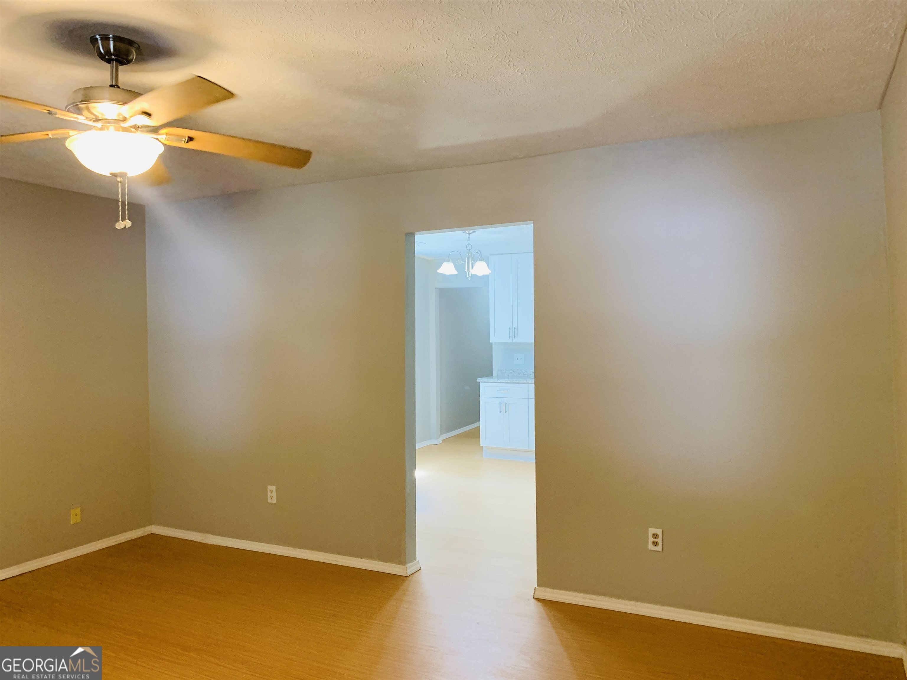 7 Burdette Place, Unit A Newnan, GA 30263 - Photo 5 of 18 an empty room with a chandelier fan and wooden floor