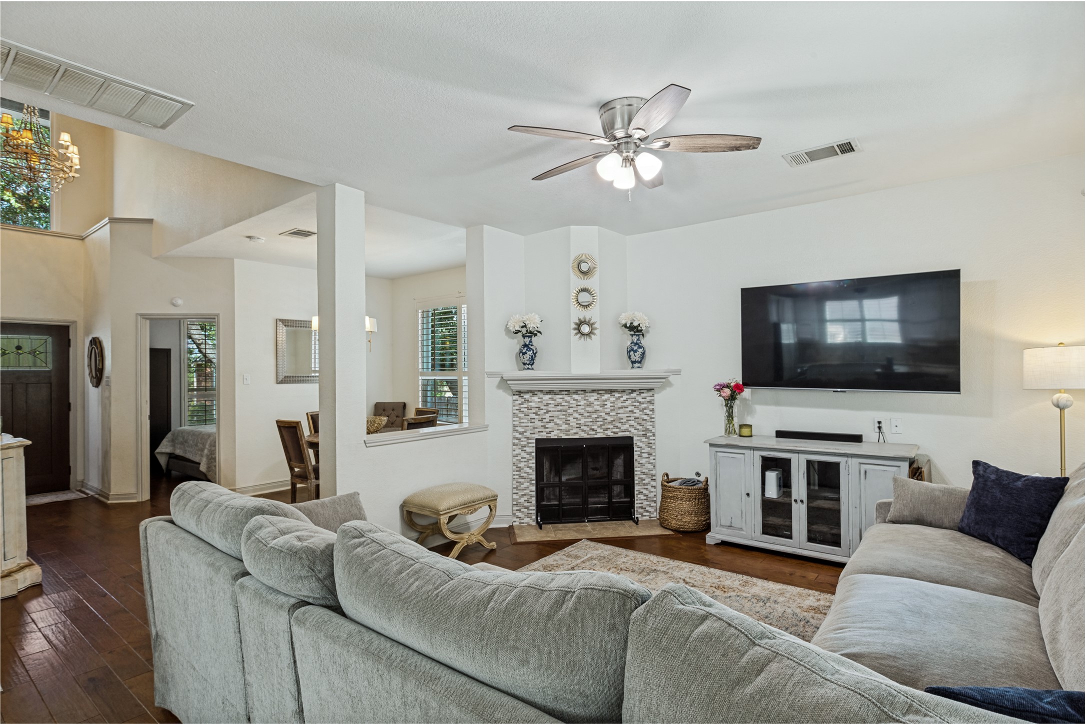 3803 Caney Creek Road Austin, TX 78732 - Photo 3 of 21 Rich hardwood floors complement the cozy tiled fireplace in this open main living space.