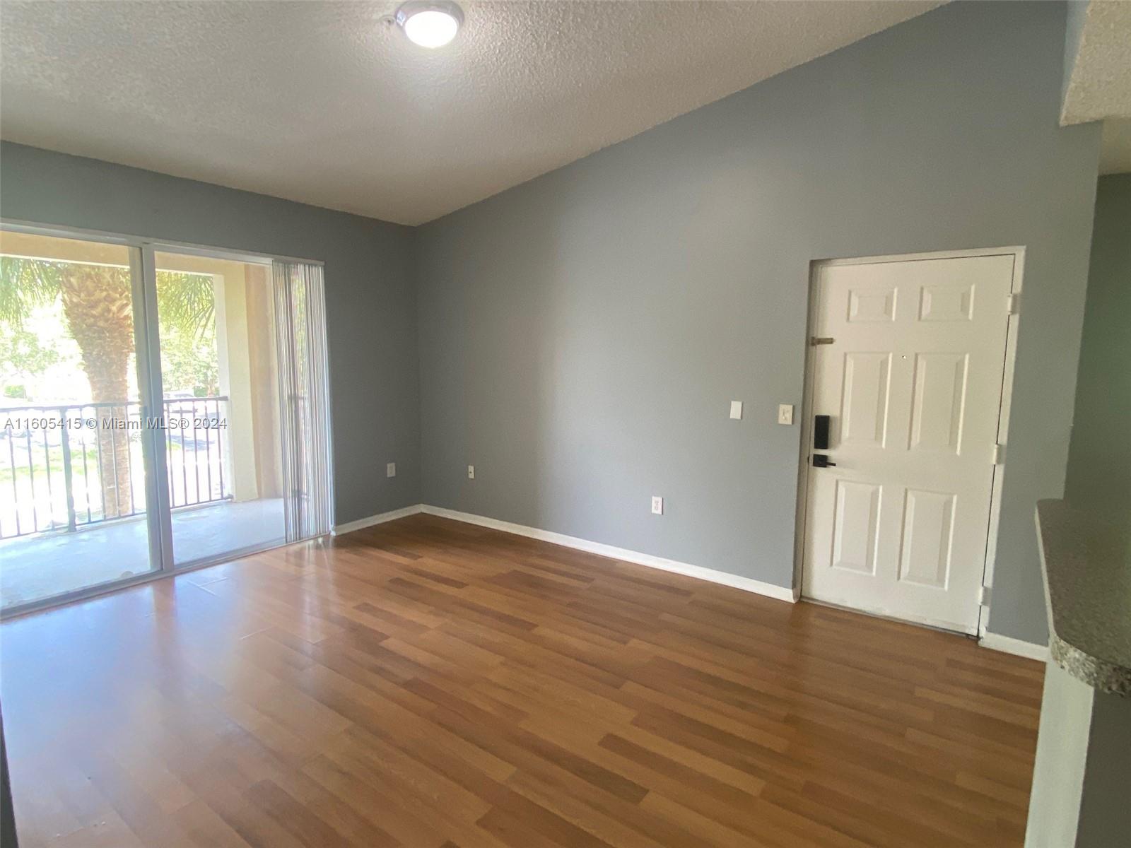 8050 North Nob Hill Road, Unit 201 Tamarac, FL 33321 - Photo 2 of 16 a view of an empty room with wooden floor and a window
