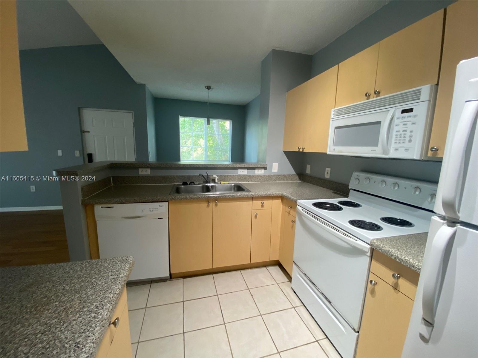 8050 North Nob Hill Road, Unit 201 Tamarac, FL 33321 - Photo 8 of 16 a kitchen with a stove a sink and a microwave