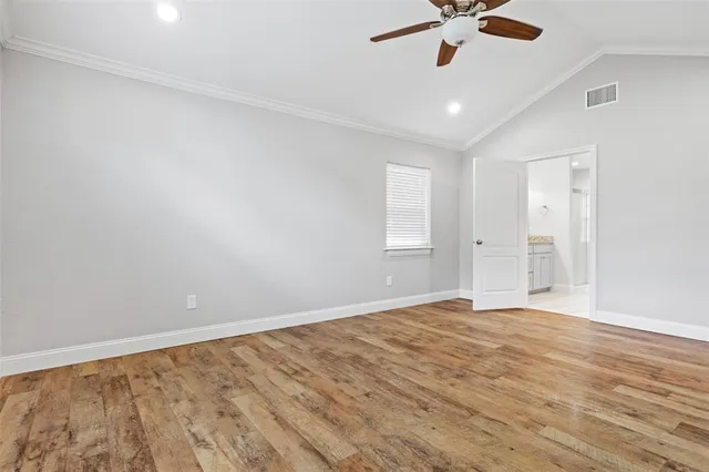 an empty room with wooden floor cabinet and windows