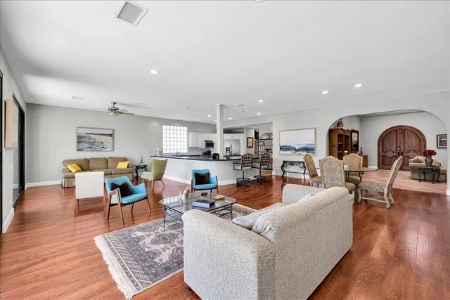 a living room with furniture kitchen view and a wooden floor