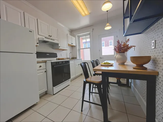 a kitchen with stainless steel appliances kitchen island granite countertop a table chairs and a refrigerator