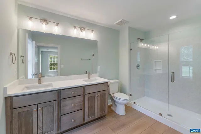 a bathroom with a shower sink vanity mirror and toilet