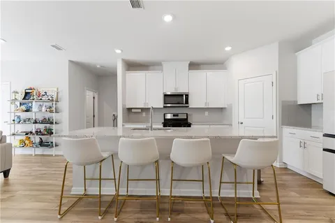 a kitchen with stainless steel appliances a dining table chairs and a refrigerator