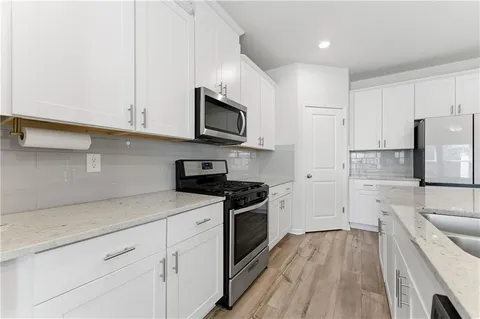 a kitchen with cabinets stainless steel appliances a sink and wooden floor
